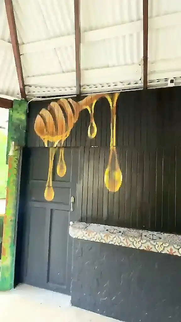 Barra pintada de negro con una cuchara de miel goteando