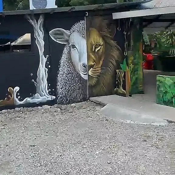 Mural del cordero y el león junto a un chorro de leche en la fachada del local