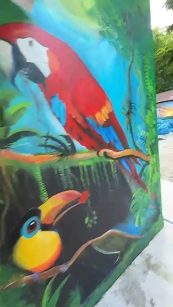 Mural de una lapa roja y un tucán entre la selva