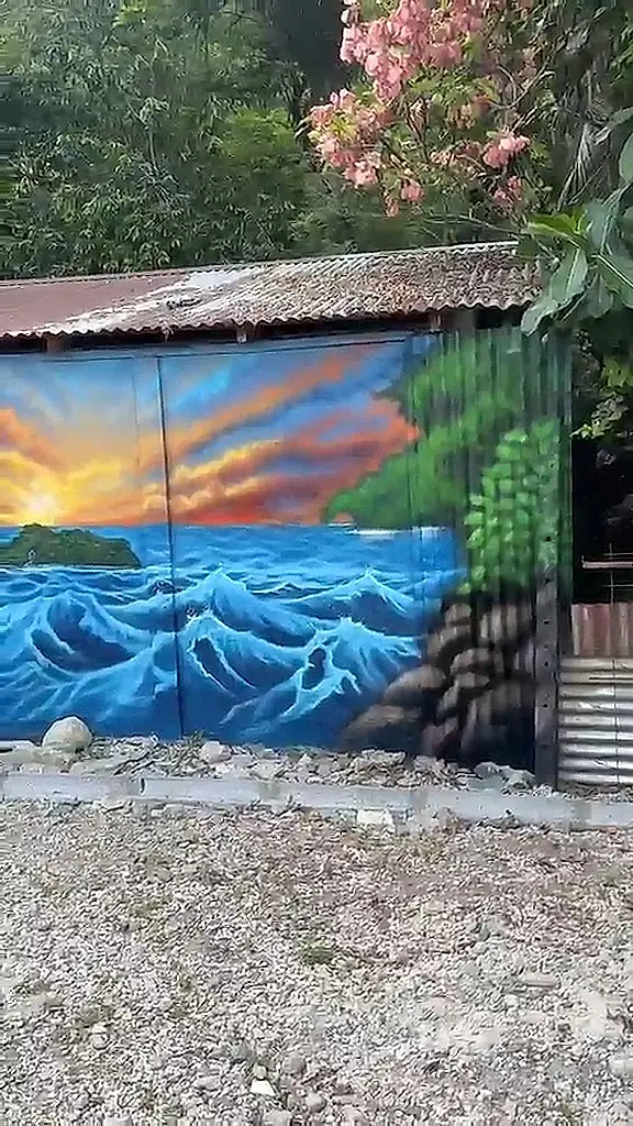 Pared con un mural del mar y una isla al atardecer, entre flores